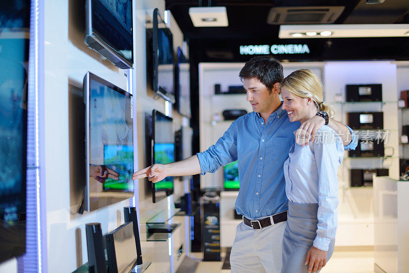 年轻夫妇在消费电子商店买电视