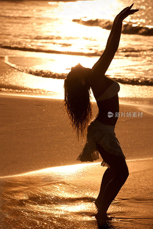 日落时分，海滩上跳舞的女人的剪影