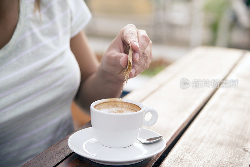 一个女人在咖啡杯里倒糖的特写