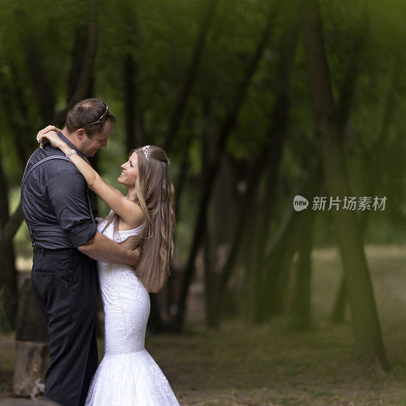 新郎和新娘在公园树旁的婚礼陶艺上