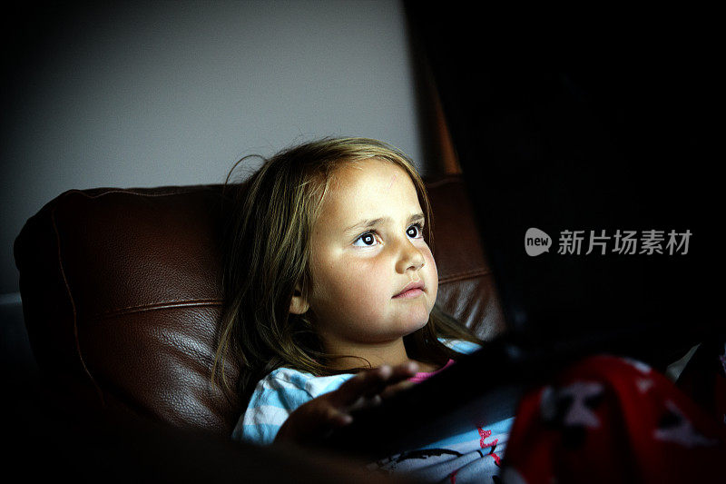一个六岁小女孩晚上在用笔记本电脑