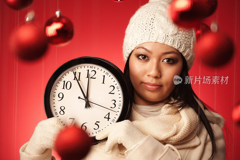 严肃的模特在冬季时装举行圣诞购物截止时钟