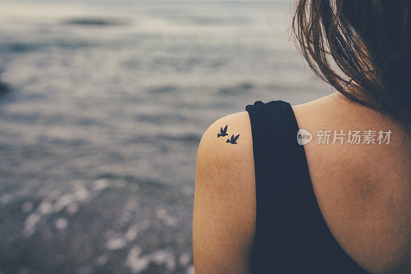 肩上有鸟纹身的女孩。自由的概念