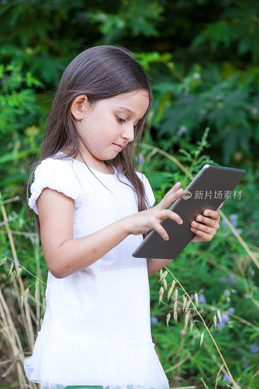 小女孩在树林里玩平板电脑