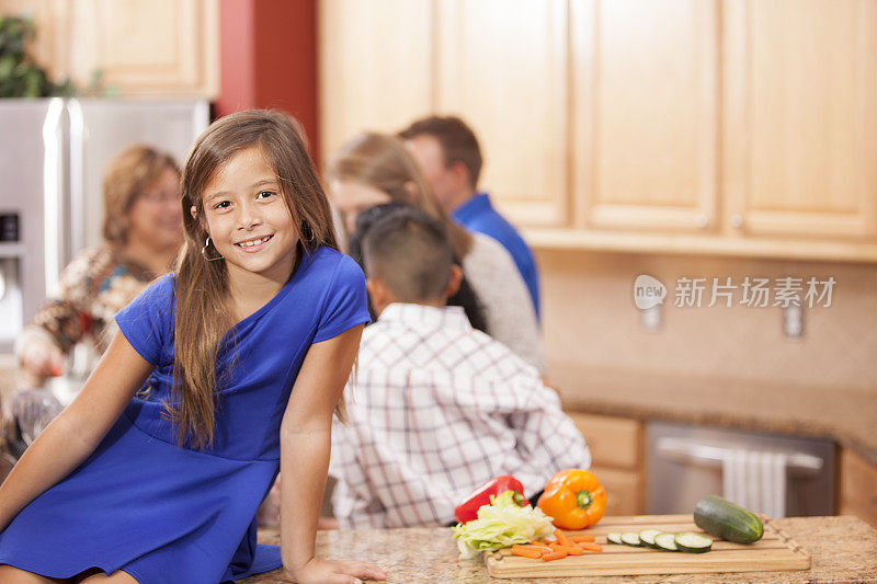 几代同堂的家人和朋友聚在厨房准备晚餐。