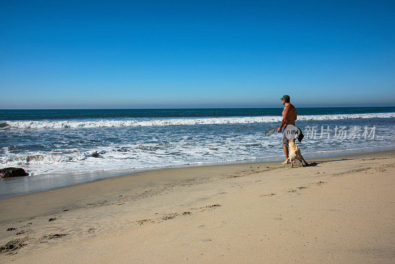 一个人和他的狗在海滩上玩
