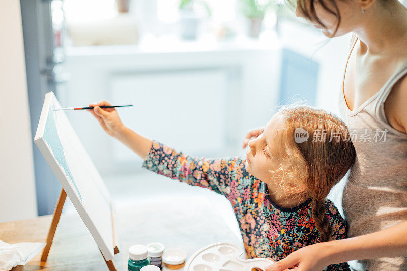 千禧妈妈和她的女儿在画布上画画