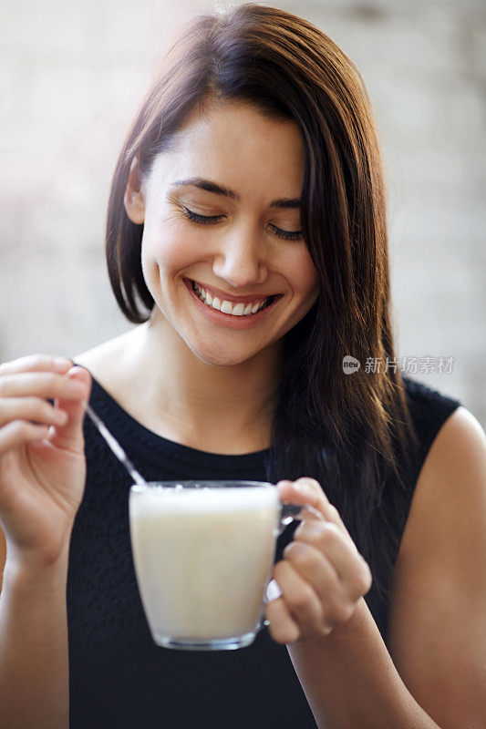 女人搅动拿铁杯微笑的肖像