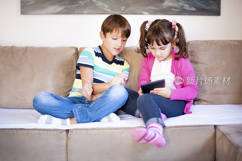 男孩和女孩在客厅里玩平板电脑，