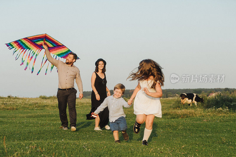 一家人带着两个孩子在草地上玩风筝