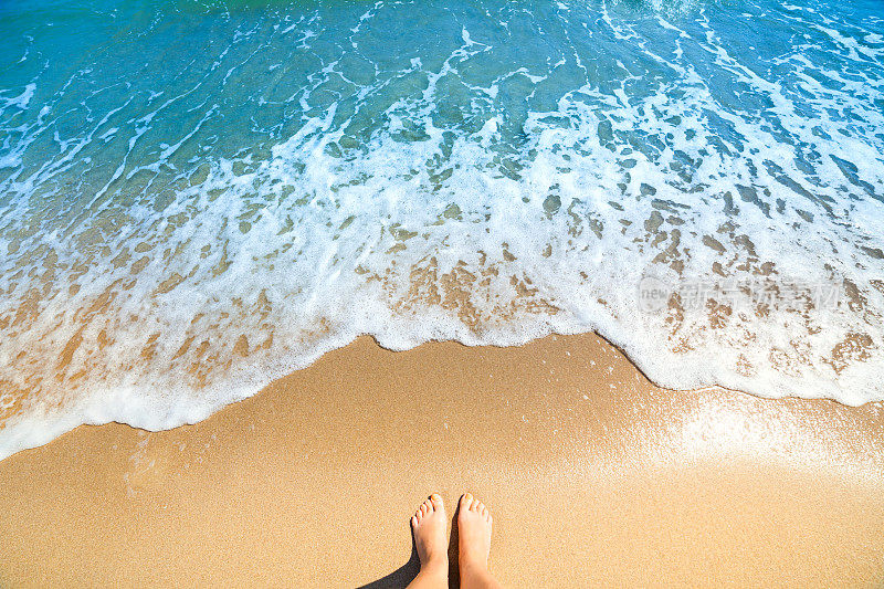 海水的泡沫，海浪和赤裸的脚在沙滩上