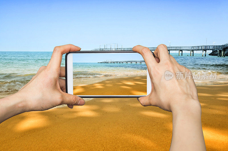 在沙滩上用手机拍照的女孩