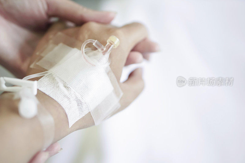 医院里，一名护士小心翼翼地用静脉导管握住病人的手