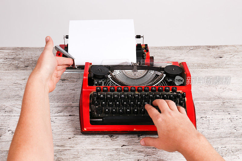 红色老式打字机，桌上放着白纸