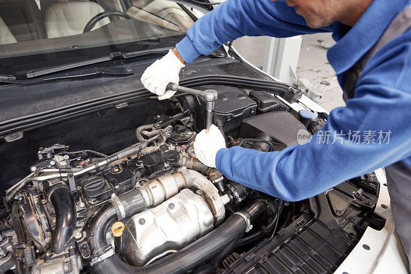 汽车修理工在修理厂修理汽车发动机。