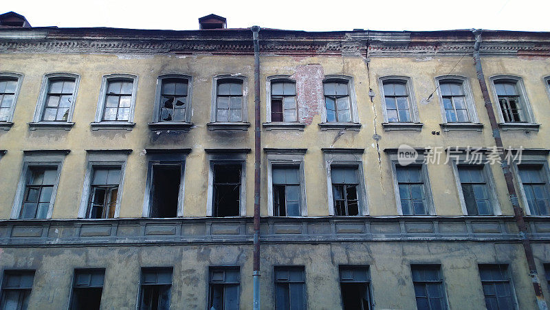 一座废弃的旧建筑，窗户附近的墙上有火烟的痕迹
