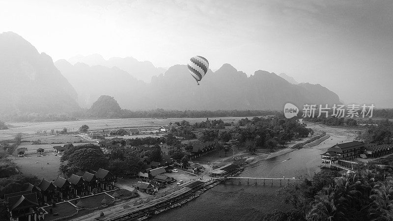 无人机鸟瞰图:日落时，热气球飞越老挝万荣的南宋河。黑色和白色