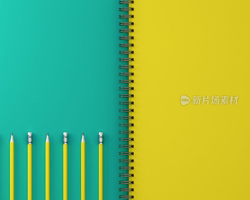 速写本和黄色粉笔在绿色和黄色的背景。俯视图，平放。最小的工作空间。工作以计划的概念实现目标。