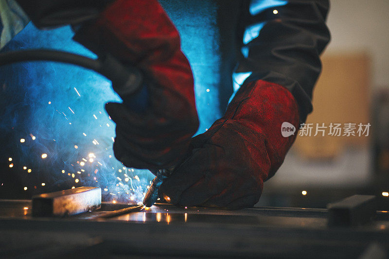年轻的专业焊工,打磨焊接金属棒材
