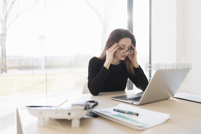 带着笔记本电脑在办公室工作的压力很大的女人