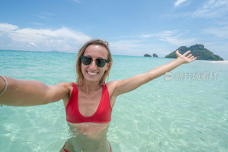 一个年轻的女人在泰国岛屿的原始清澈的水田园般的海滩上自拍。人们旅行豪华度假乐趣和酷的态度概念