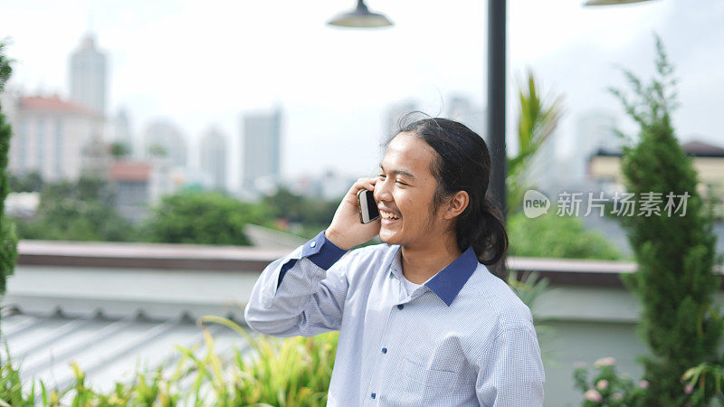 亚洲男人用智能手机打电话时的笑脸