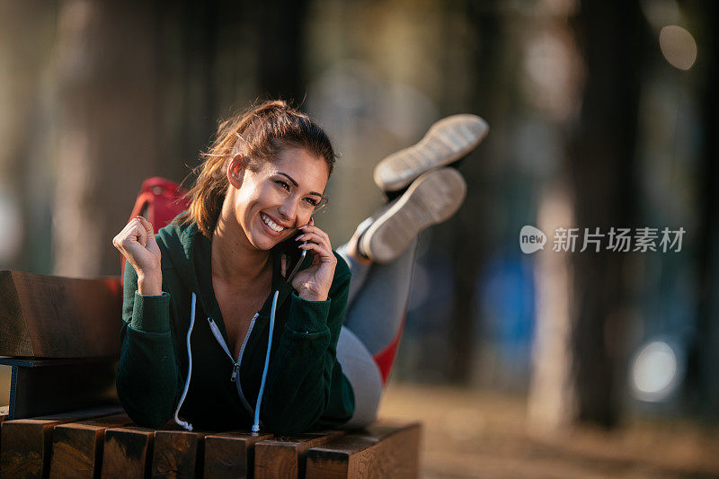 漂亮的年轻运动女性与智能手机在户外