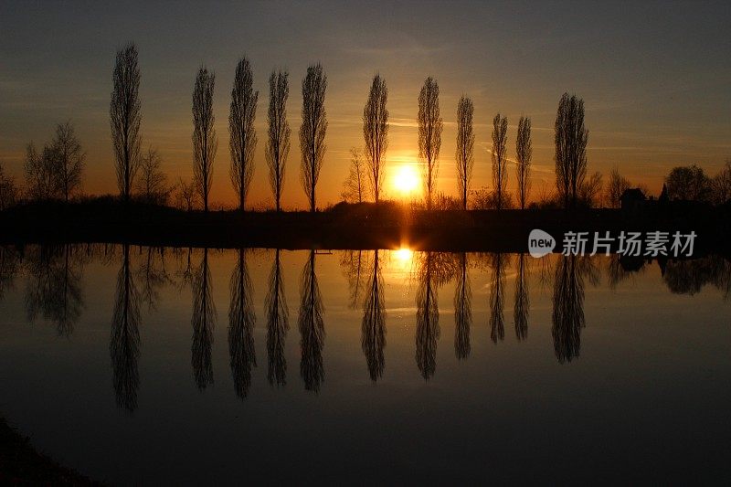 夕阳西下，树木倒映在湖面上