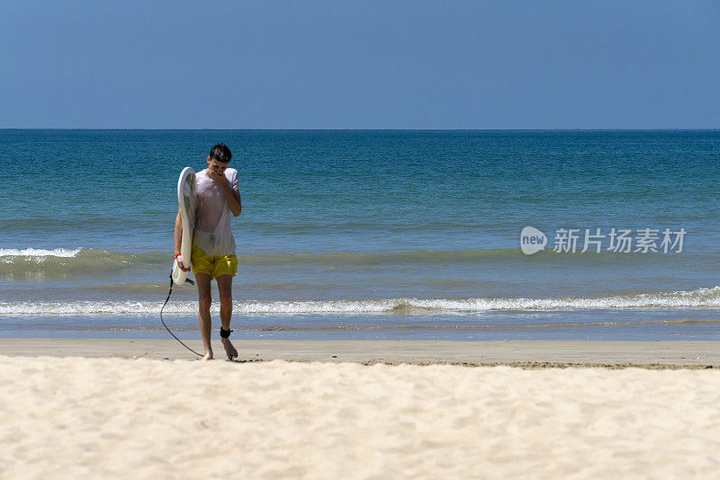 一个年轻人带着冲浪板离开帕卡朗海滩