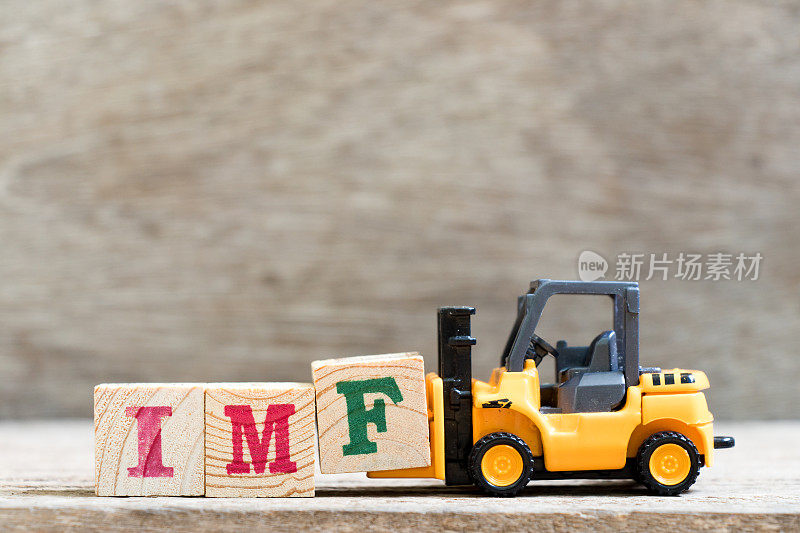 玩具叉车托架上的字母块f以单词IMF(国际货币基金组织的缩写)为背景