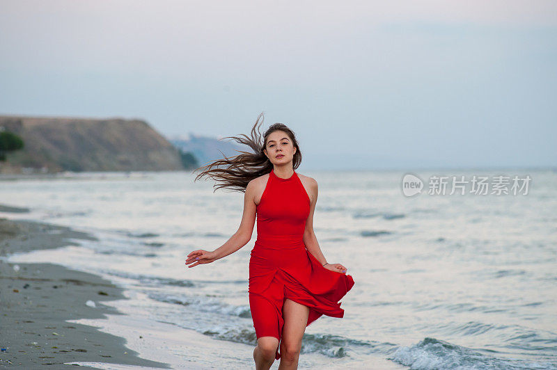 穿红衣服的年轻女子在海滩上跑步