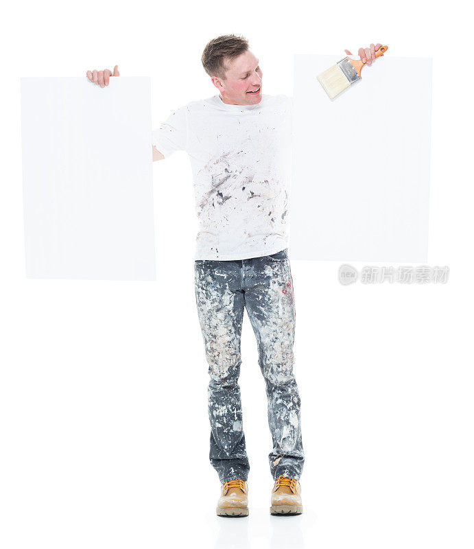 年轻的白色画家，他的衣服上有污点拿着一个小标语牌-拿着两个标语牌