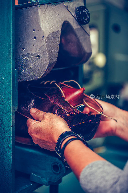 在制鞋行业中，经验丰富的鞋匠使用专用机器将鞋子放到模具上。