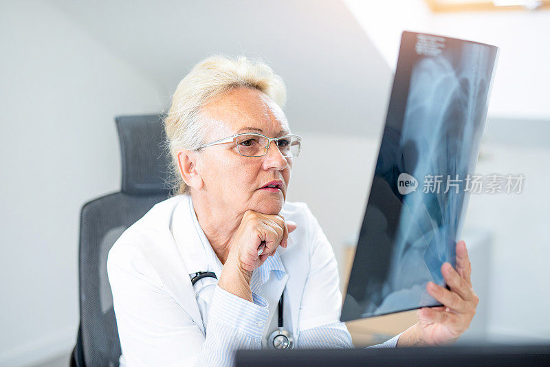女高级医师正在分析一名女性肺部x线片。