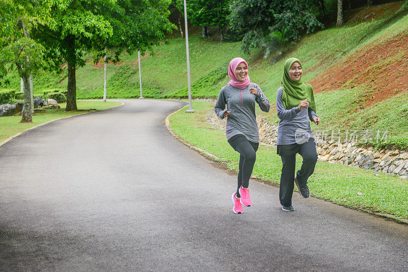 年轻的亚洲穆斯林女运动员戴着头巾在跑道上跑步