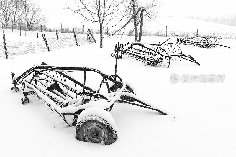 景区里有三台生锈的旧农机在雪地里。