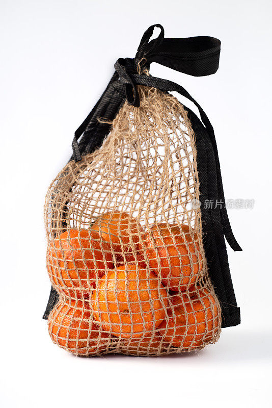 在白色背景上的自然材料网格中的柑橘类水果。Eco-packaging。明亮的橙色的橘子。自然光线。