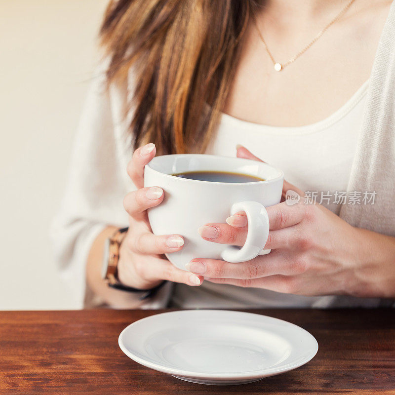 特写的一个不认识的女人在咖啡杯上暖手