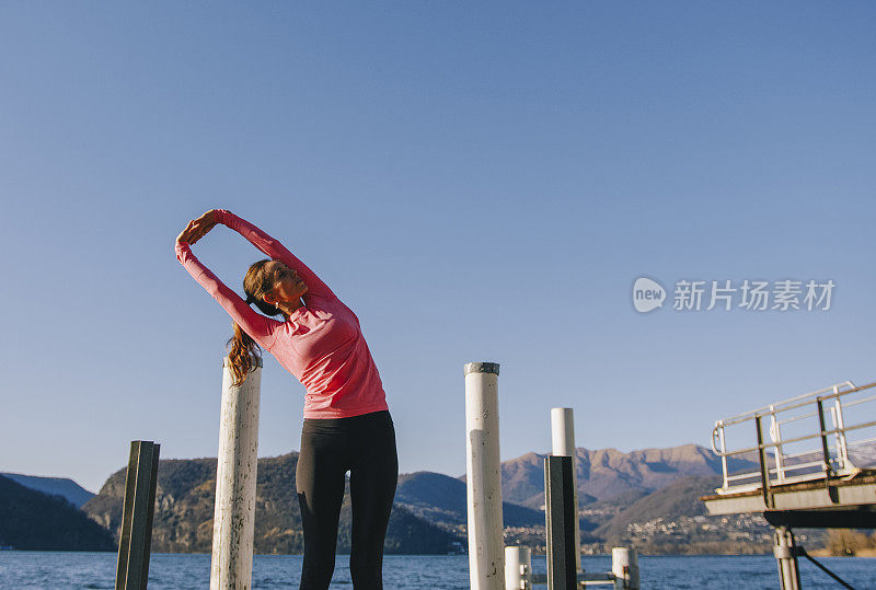 女子在湖边的码头上表演瑜伽动作