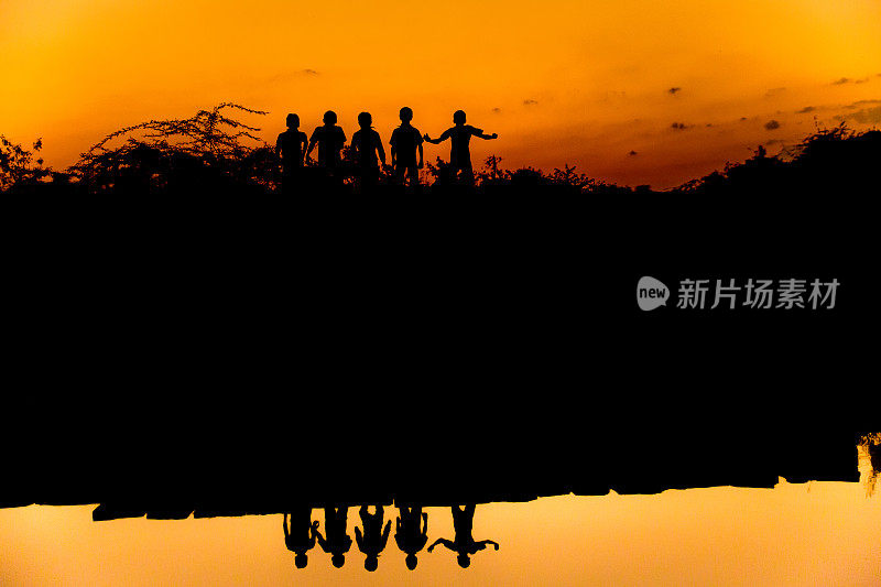 一群徒步旅行者站在湖上的剪影