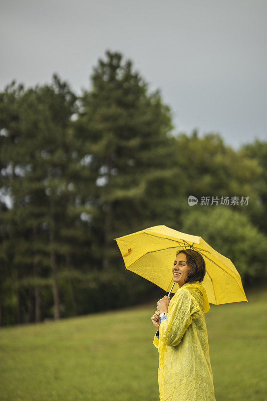 快乐的女人微笑着行走在雨天