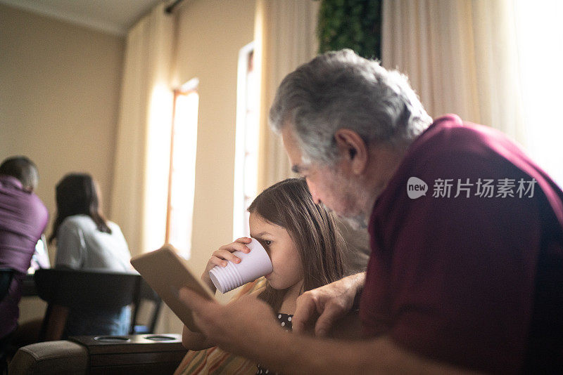 祖父和孙女在家里使用数码平板电脑