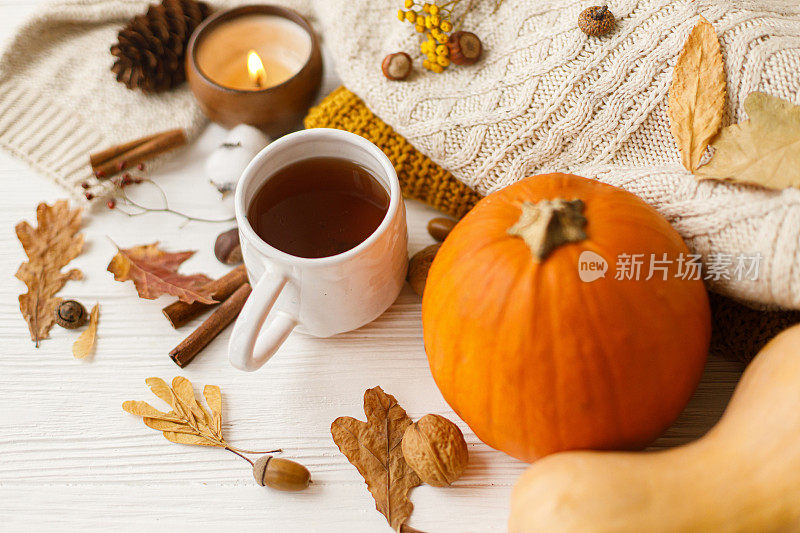 温暖的茶，南瓜和香料，舒适的针织毛衣，秋叶和蜡烛的背景