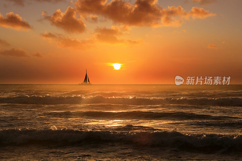 剪影的帆船漂浮在夕阳下的橙色海景上