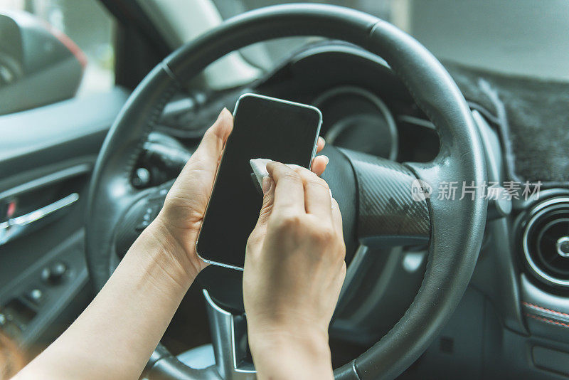 女人在车里用抗菌擦拭布清洁智能手机