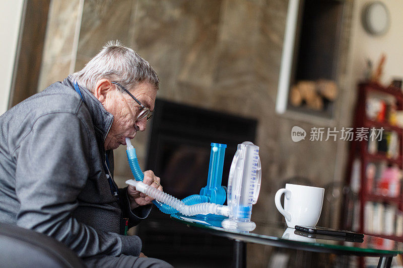 老人使用一次性肺活量计锻炼他的肺，以保持肺泡充分充气，这样他可以呼吸得更好。