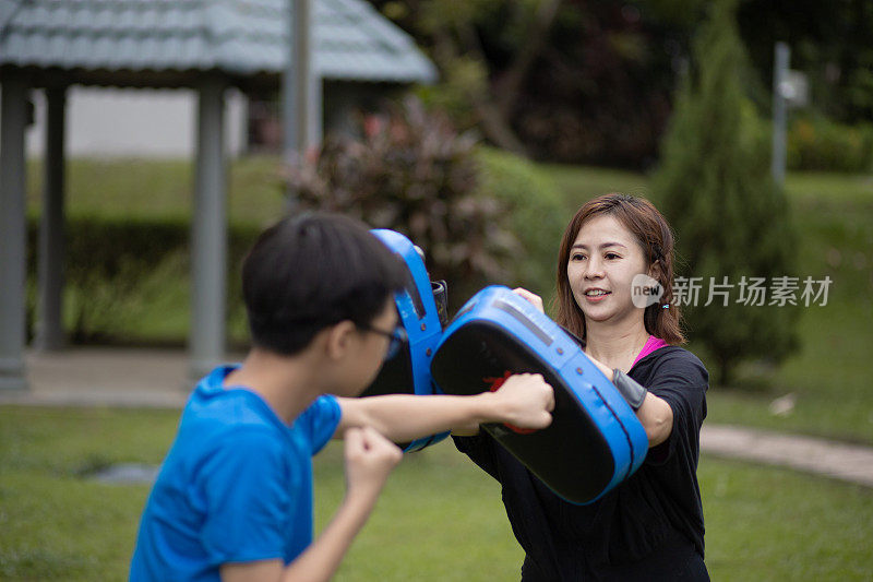 亚洲华人妈妈和孩子们在公园里玩得很开心。他们在训练跆拳道。泰拳，武术