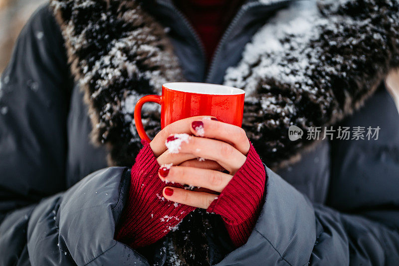 手里拿着杯子的女人在雪中瑟瑟发抖