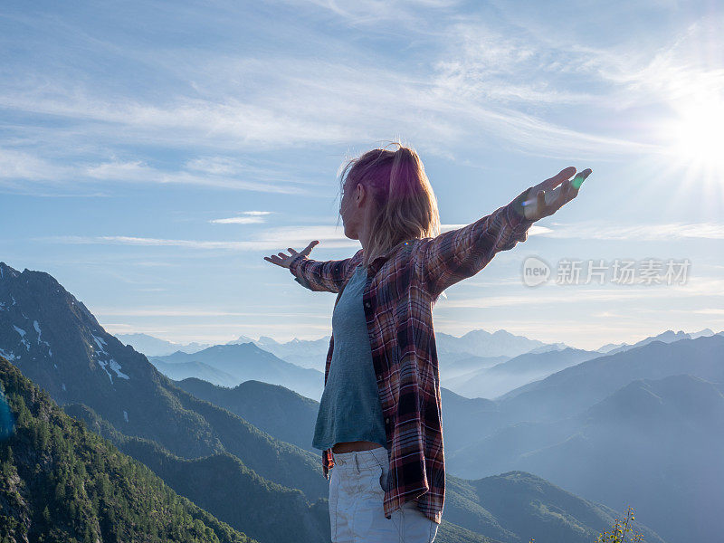 一个徒步旅行者双臂伸开站在山顶上