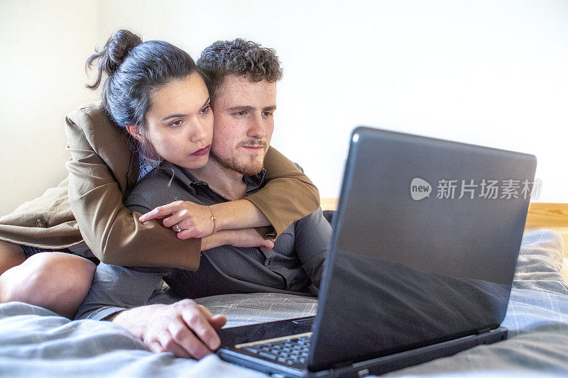一对夫妇在床上使用笔记本电脑